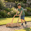 Smiling boy plays outdoors with handcrafted wooden Montessori push toy from Balance mee.