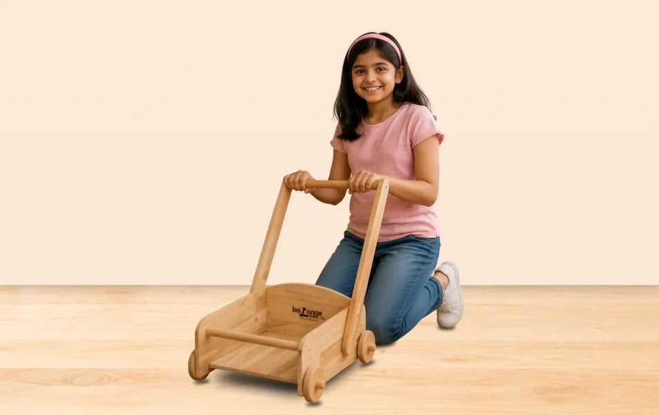 Smiling boy pushes handcrafted Montessori wooden cart with books and teddy bear outdoors