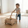 Smiling toddler plays with handcrafted Montessori wooden push toy and blocks indoors