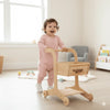 Smiling toddler pushing Balance mee wooden Montessori walker in bright playroom