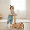 Smiling toddler playing with handcrafted wooden Montessori push toy in bright room