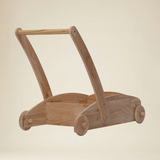 Toddler practicing first steps with a safe wooden walker trolley